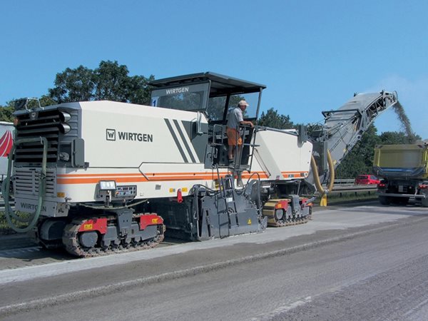 Milling machine operator working a highway stretch in daylight
